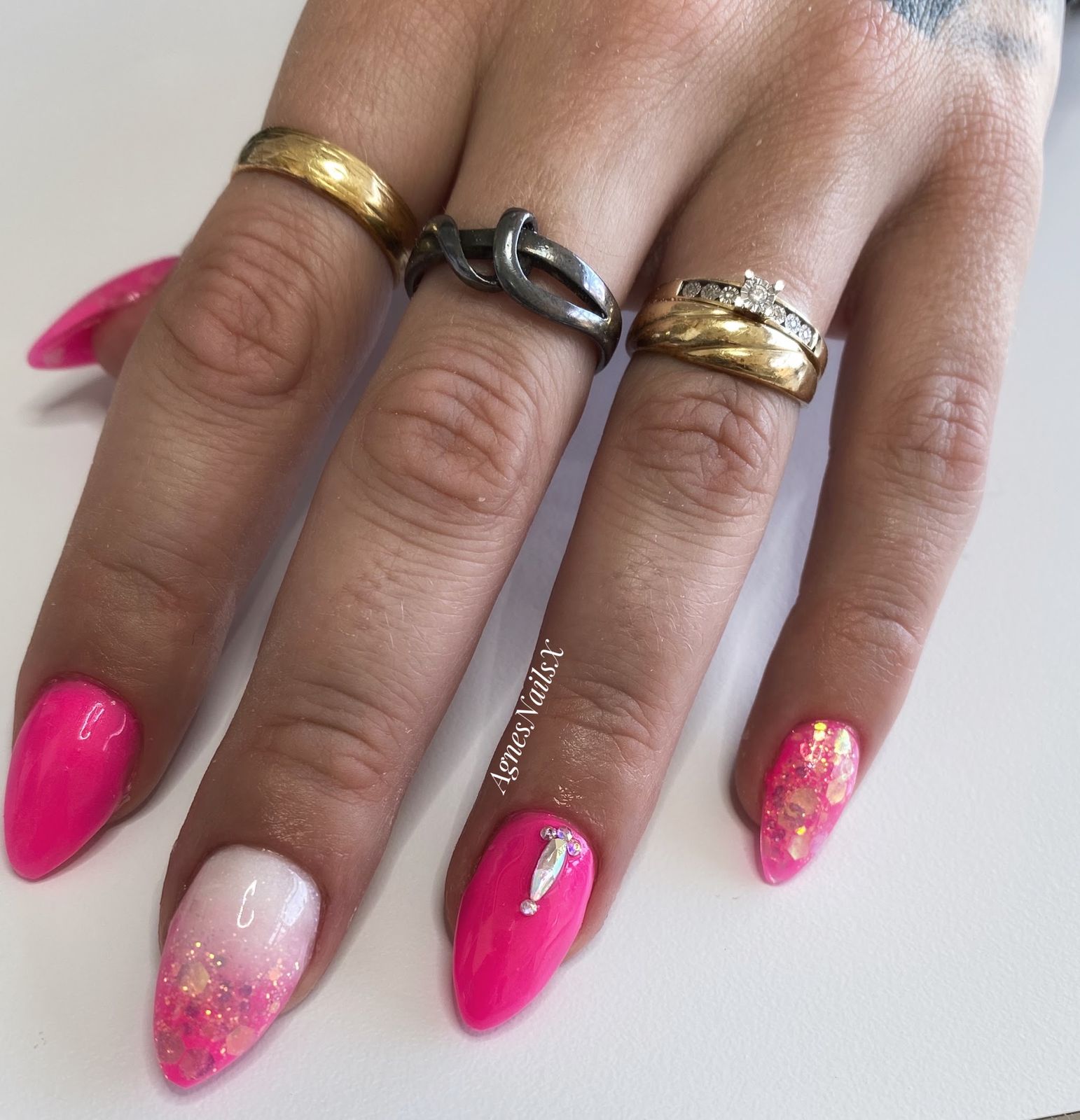 Knalroze amandelnagels met een glitter-ombré en een steentje
